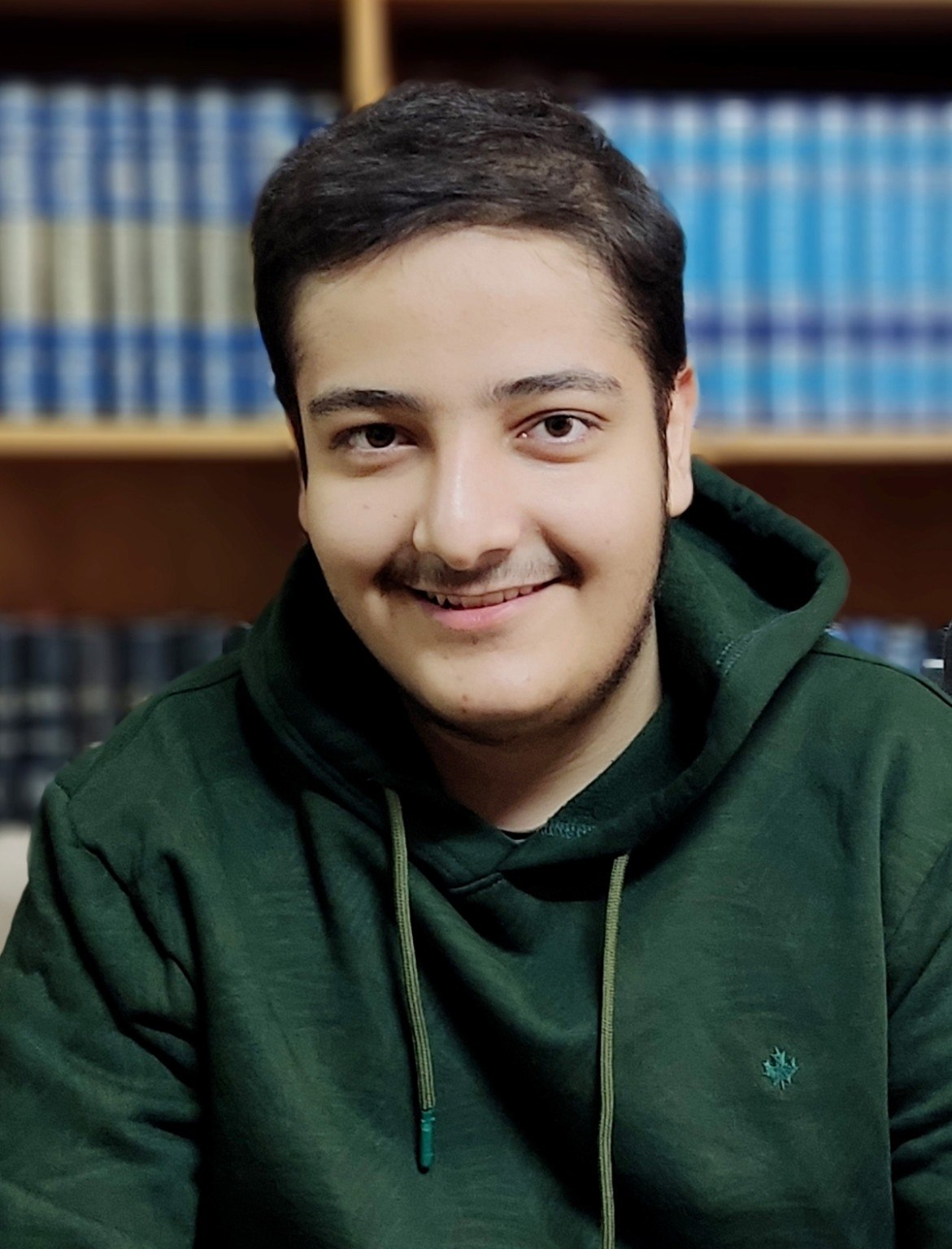 چهرهٔ خندان سید محمد مهدی رکنی حسینی، در کنار قفسهٔ کتابها